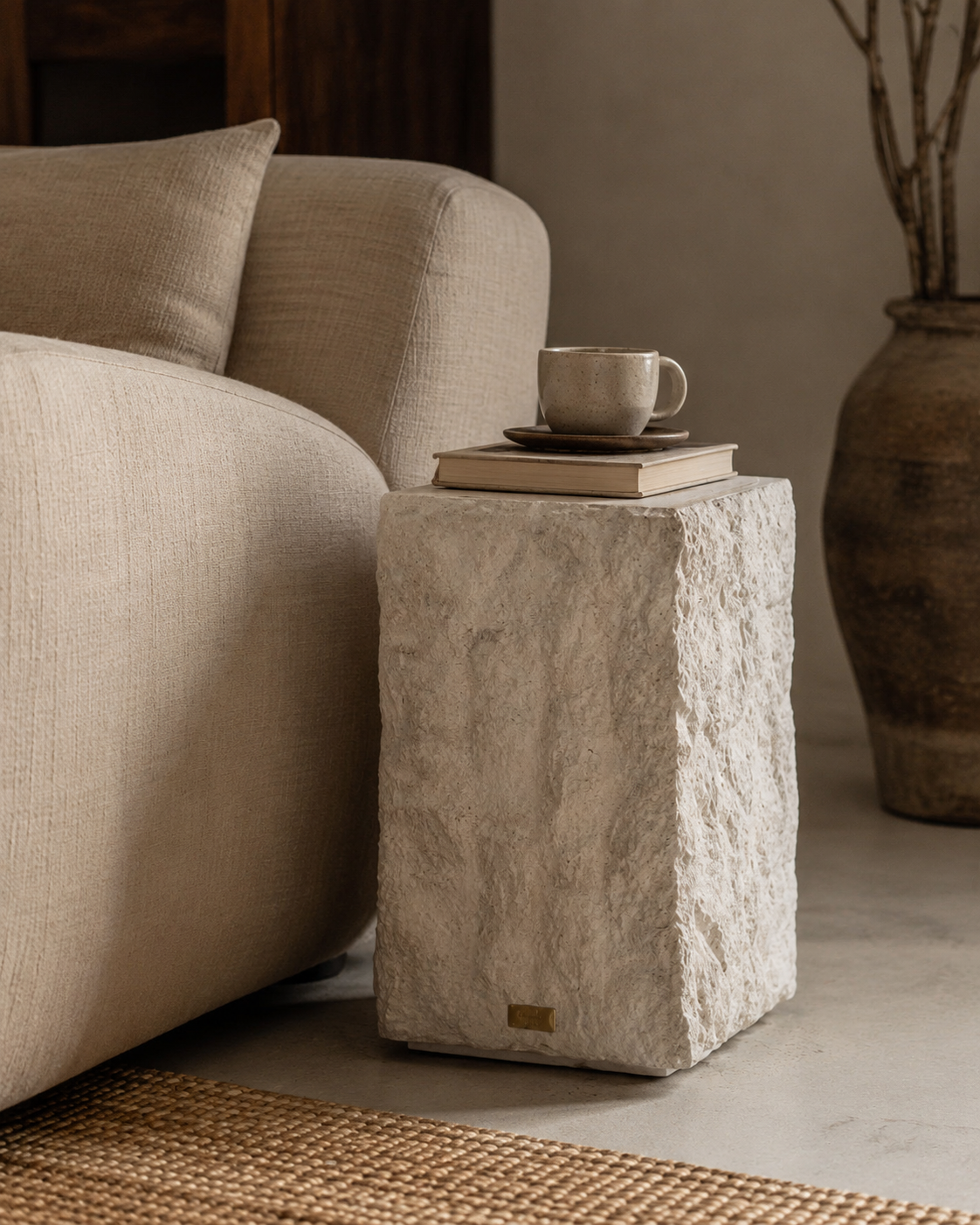 Handmade plaster side table beside a bouclé sofa