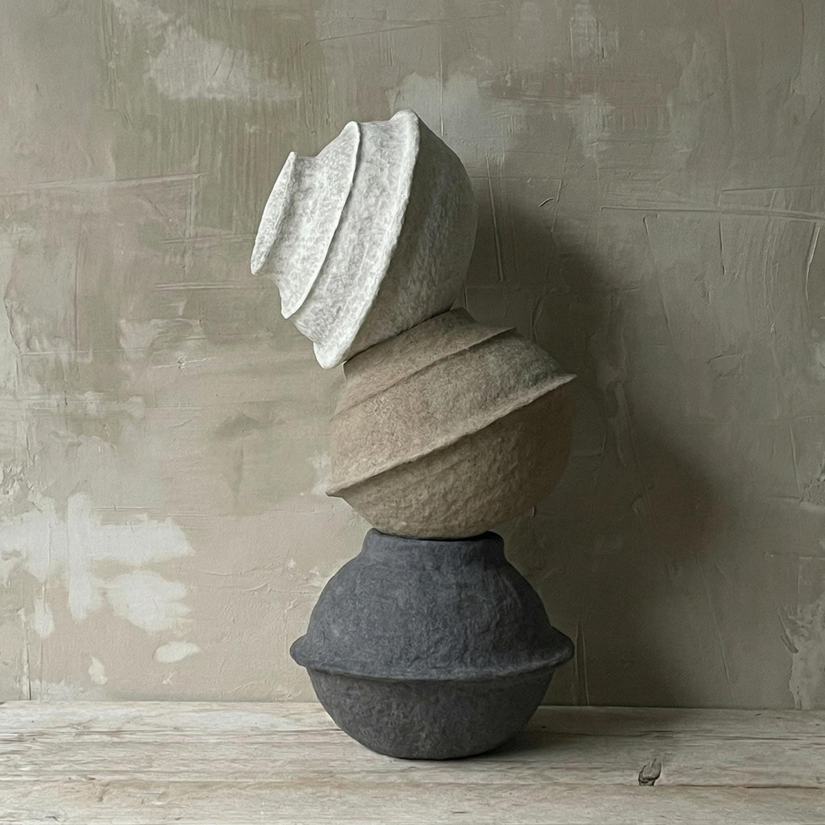Plaster Column Totem against a weathered plaster wall on a wooden floor